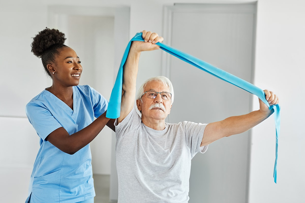 Doctor or nurse or physiotherapist caregiver exercise with senior man and woman couple at clinic or nursing home