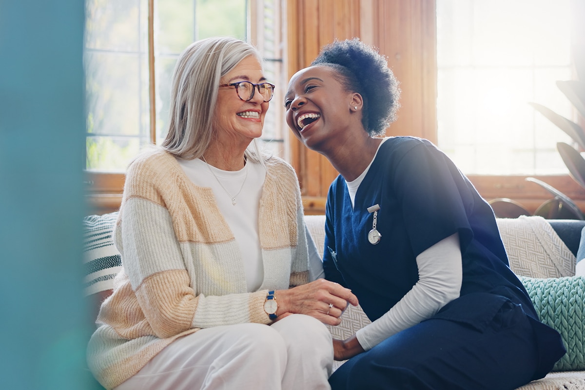 Senior patient, funny or happy caregiver talking for healthcare support at nursing home clinic. Smile, women laughing or nurse speaking of joke to a mature person or woman in a friendly conversation.